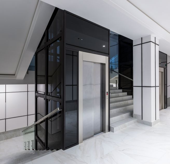 Instalación de ascensor moderno con cabina acristalada en un edificio
